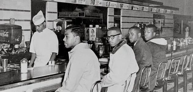 A black and white photograph of four students–Joseph McNeil, Franklin McCain, Ezell Blair Jr., and David Richmond–seated at the “whites only” counter to protest racial segregation. Photo Source: Jack