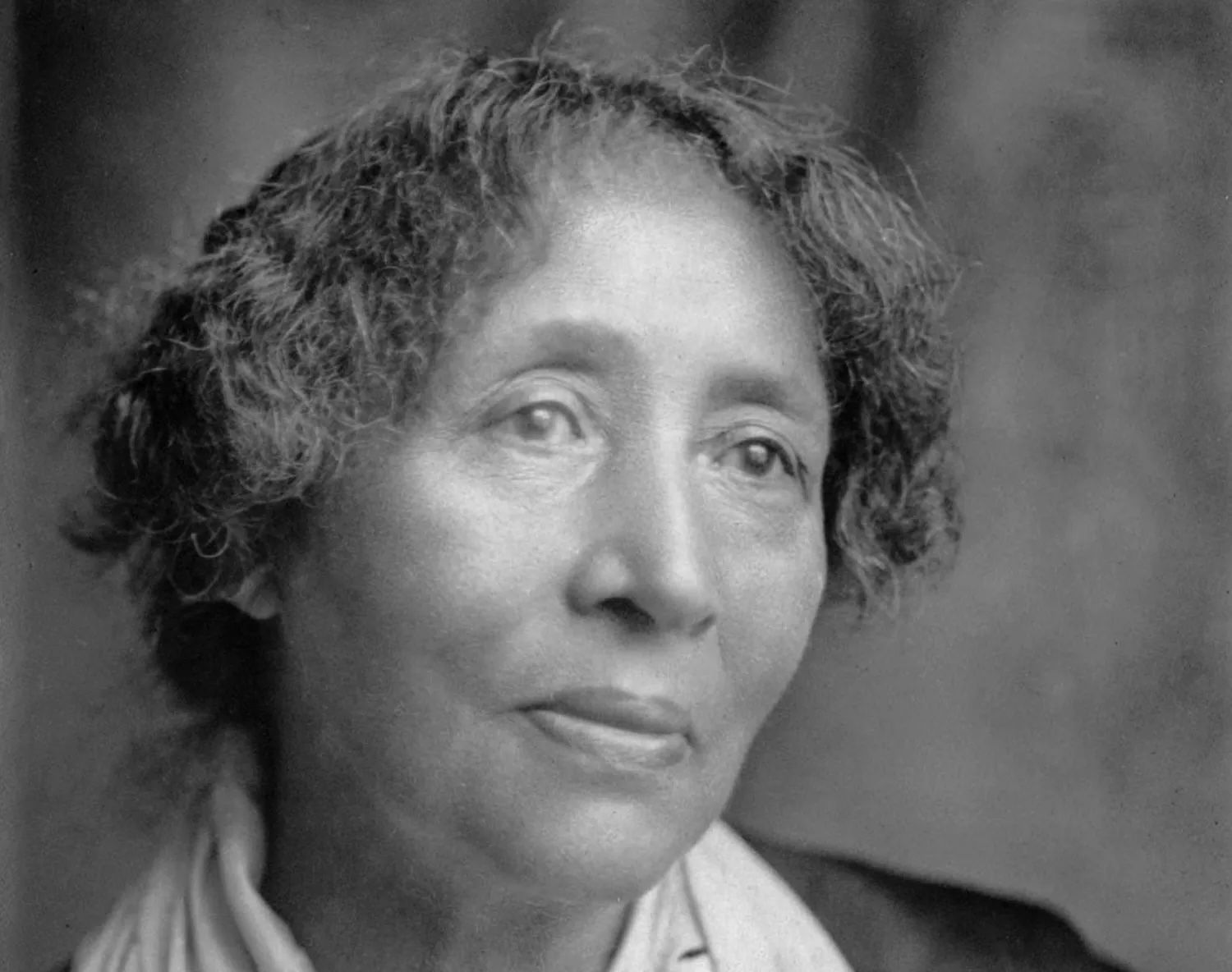 A black and white photograph of Parsons, later in life, looking wistfully away from the camera. Photo Source: Black America Web
