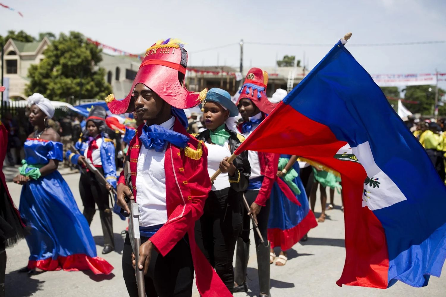 A photograph of a young man dressed as independence hero Jean Jacques Dessalines marching with others celebrating Haiti’s independence in 2018. Photo Source: AP.
