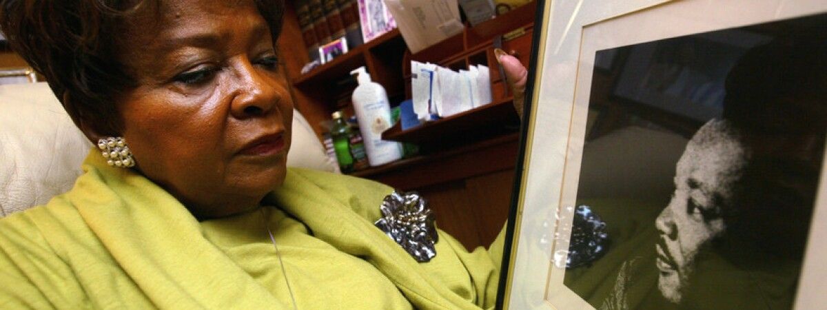 A color photograph of Wyatt, taken later in life, showing her in a smart green suit looking at a black and white photograph of Dr. Martin Luther King, Jr. Photo Source: AP/Nam Y. Huh