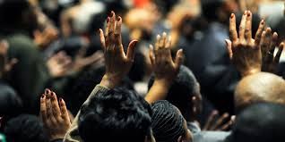 A closeup photograph of melanated hands lifted in praise at a congregation. Photo Source: LightStock / Larry Dixon Jr.