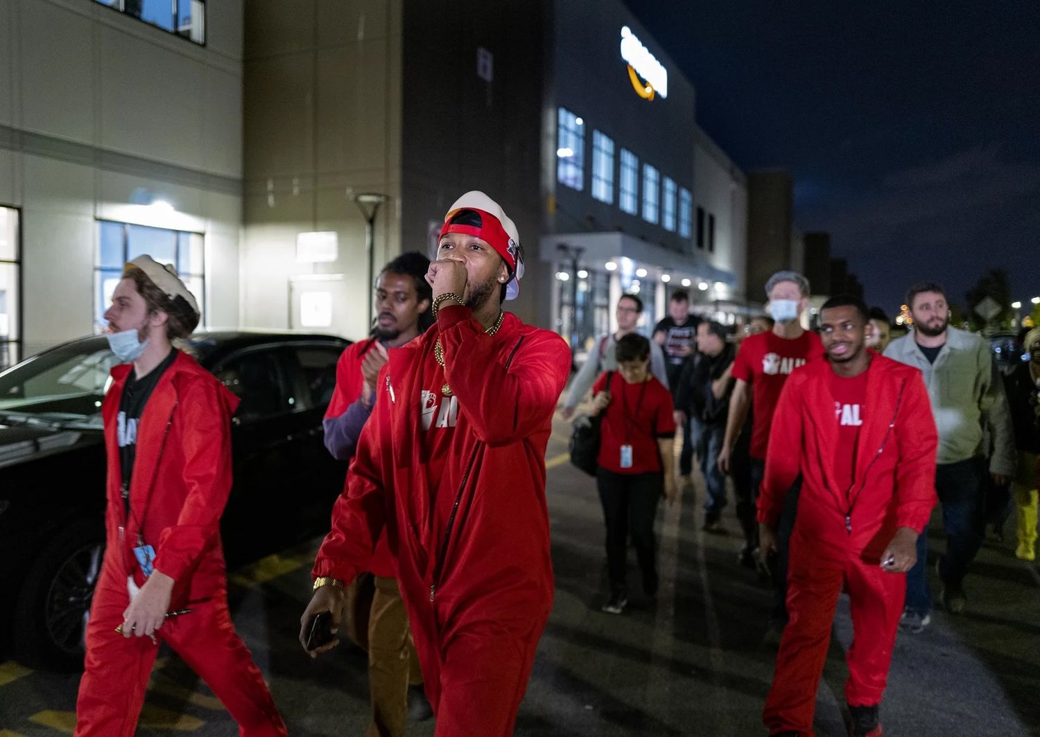 A photograph of Smalls, wearing a red jumpsuit with the ALU t-shirt underneath, marching with colleagues and chanting at the JFK8 Amazon distribution center in Staten Island on Oct. 25, 2021. Photo So