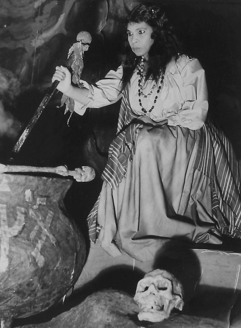 A black and white photograph of Anderson wearing a draped dress and holding a mallet, as Ulrica while performing for the Metropolitan Opera. Photo Source: PBS.