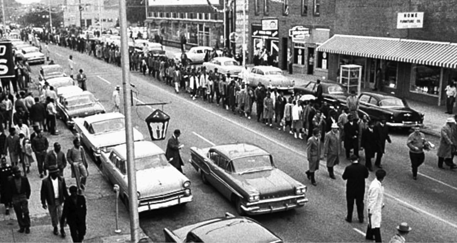 A black and white photograph from the first day of the boycott and march, which depicts dozens of Black people walking down the street. Noticeably, no buses are in sight. Photo Source: Don Cravens/Tim