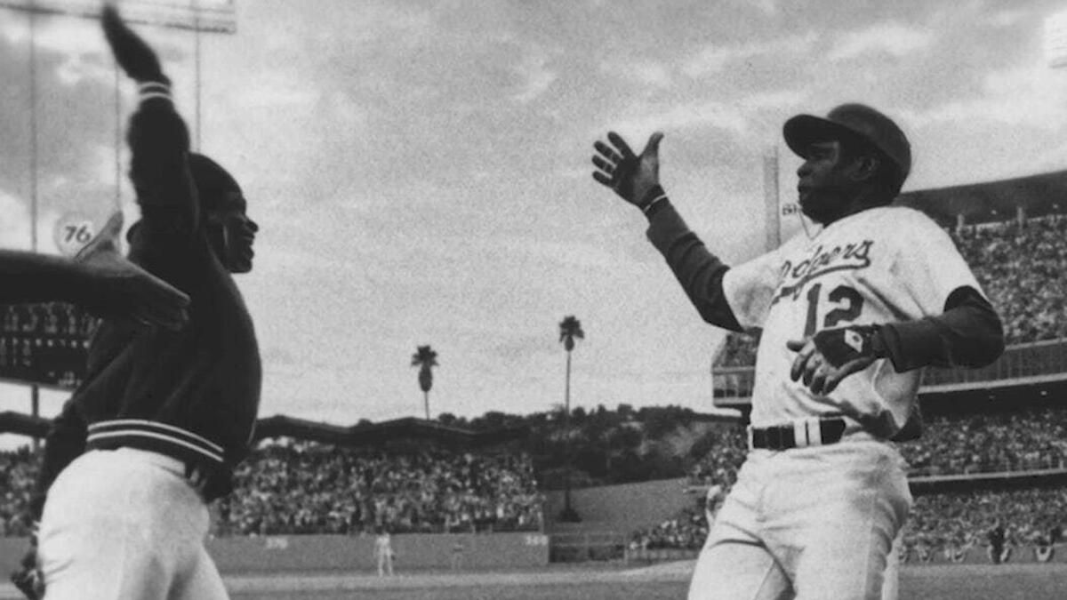A black and white photograph of Burke, left and Baker, right running toward each other with their arms outstretched, and fingers splayed, as if about to high five. Photo Source: ESPN.