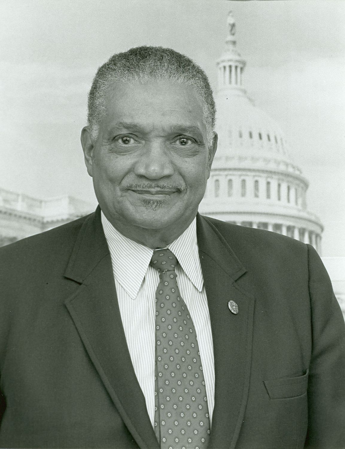 A black and white photograph of Hayes, taken for his position as a member of the House of Representatives, posing in a suit in front of the Capitol building. Photo Source: Wikipedia Commons