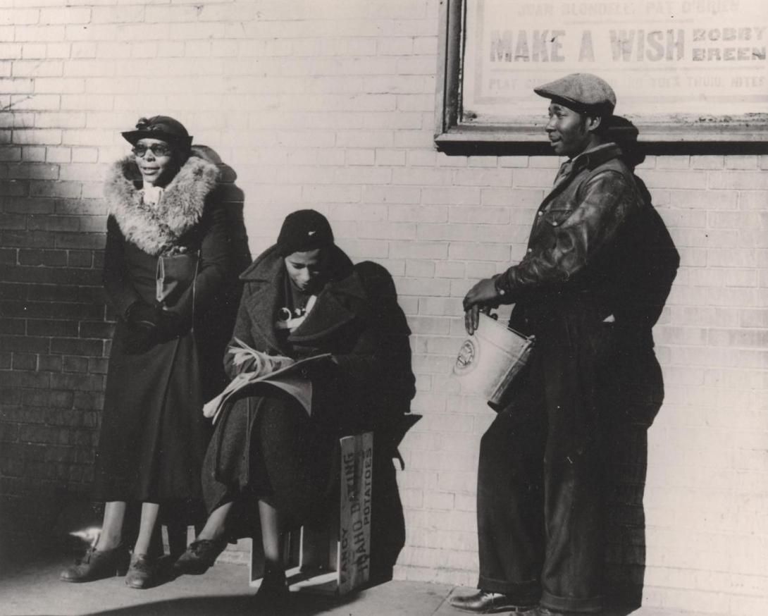 A black and white photograph of three Black unemployed domestic workers seeking employment on the streets of the Bronx, depicting what was referred to as The Bronx Slave Market, taken by Robert McNeil