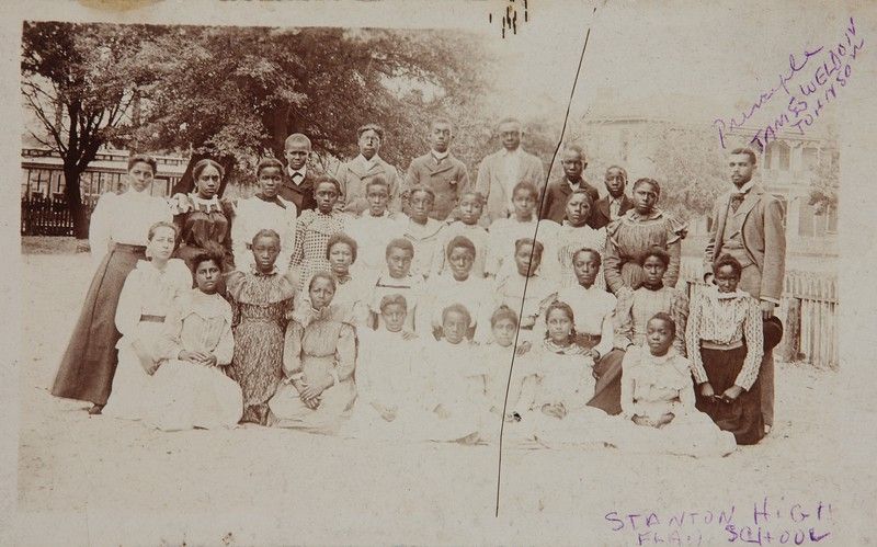 A black and white photograph of James Weldon Johnson, then principal at theStanton School, posing for a class picture with about two dozen students outdoors. Photo Source: Yale University Library