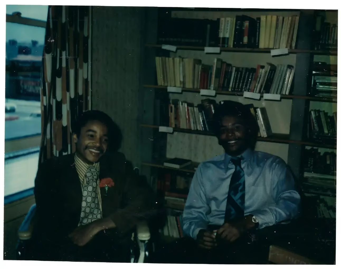 Brad and his brother, Glenn, smiling and sitting in front of a bookshelf in 1974 in the library of the Black Panther Party’s offices in Oakland, Calif. Photo Source: New York Times
